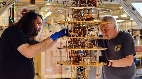 Dua orang bekerja mengatur komputer kuantum.