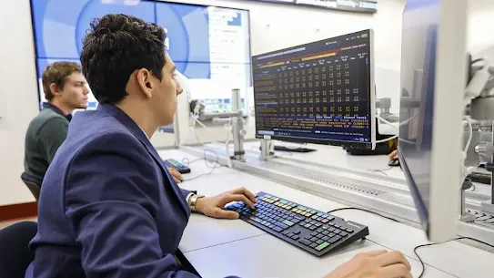 man on desktop computer sitting next other man on computer
