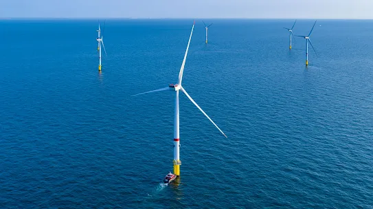 Seis aerogeneradores en el océano bajo un cielo azul