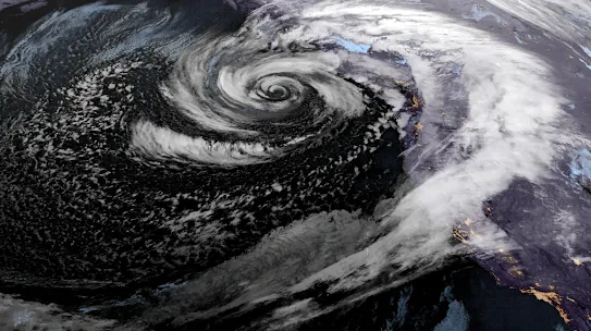 Satellite image of a powerful swirling storm system over the ocean, showing a defined eye and spiral cloud formation.