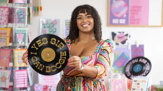 Jasmine Feehan of Dóchas Design Studio, overall winner of the 2024 You're the Business competition, stands in front of her colorful print designs.