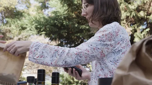 Femme commerçante tendant un sac d’épicerie à quelqu'un