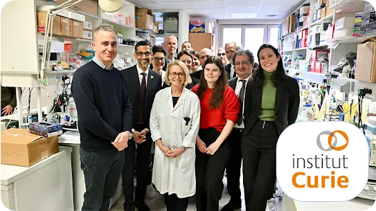 A group of researchers and staff in a lab with the Institut Curie logo in the foreground.