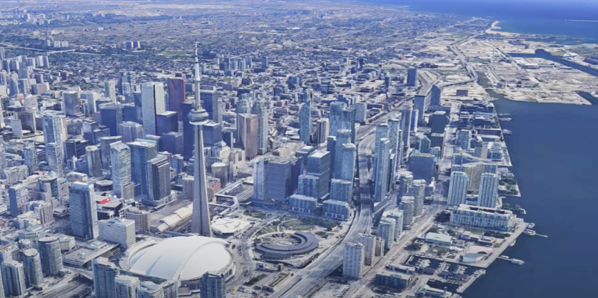 Aerial view of Toronto's downtown skyline with the CN Tower, Rogers Centre, many skyscrapers, and Lake Ontario.